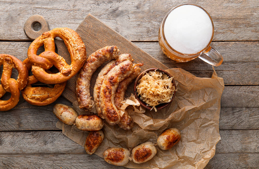 一大杯冰镇啤酒，加有巴伐利亚香肠和木制背景的零食。Oktoberfest celebration