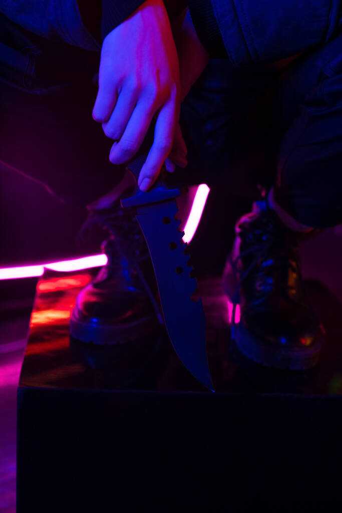 cropped view of woman in boots holding knife 