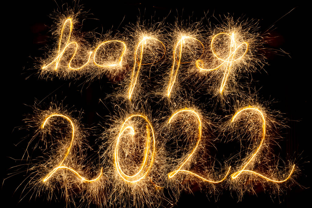 祝2022年新年快乐。快乐2022年写与闪耀的火花隔离在黑色背景与副本空间的文字。节日贺卡或横幅设计的光彩夺目、富有创意的叠印模板